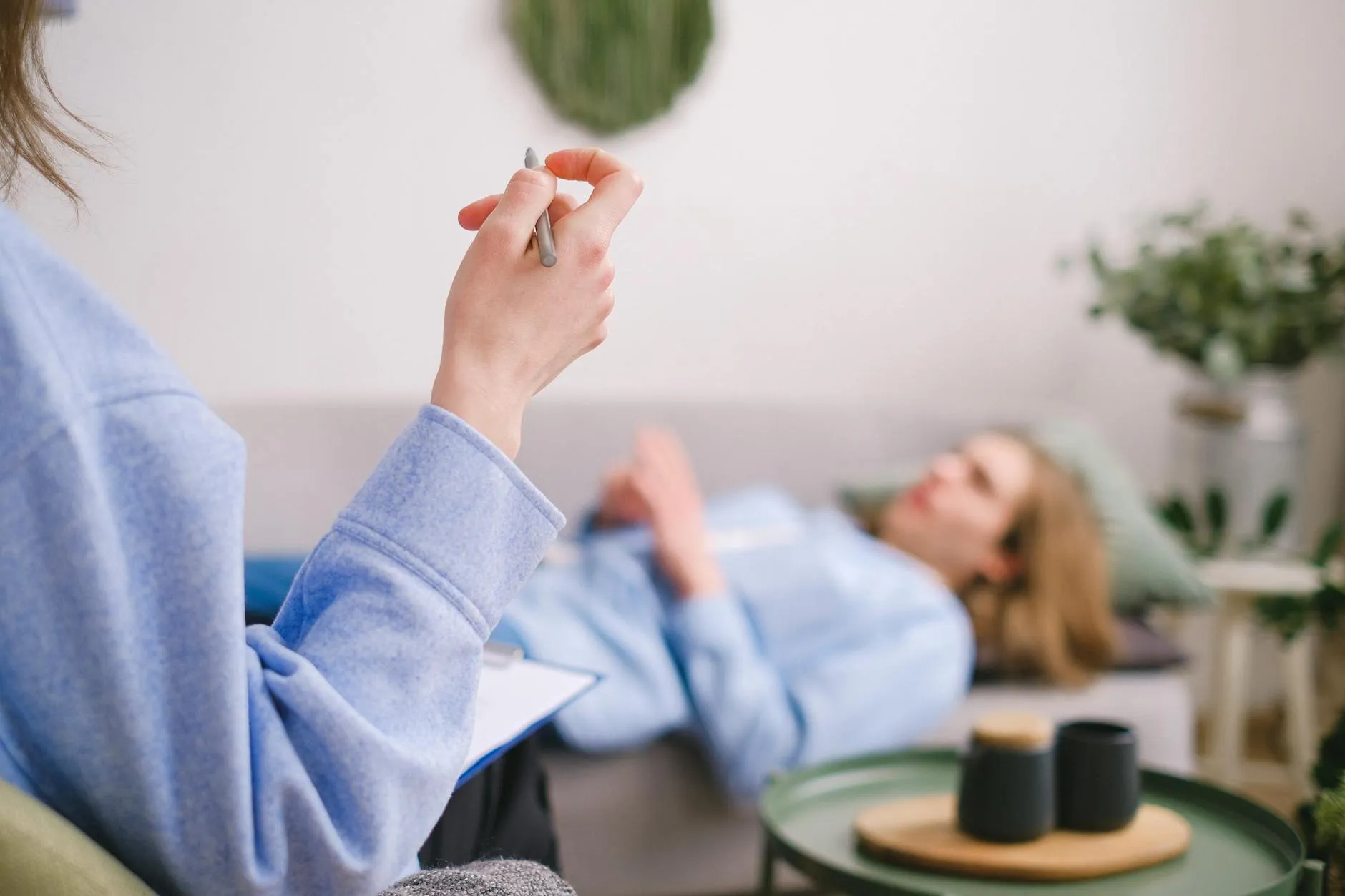 Therapist and client in comfortable session discussing CBT techniques with notebook visible