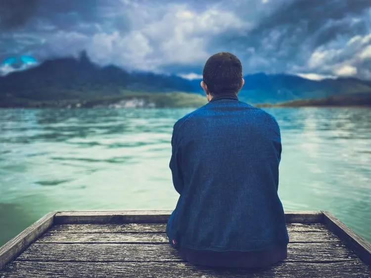 Person looking out over calm water, reflecting on their mental health journey
